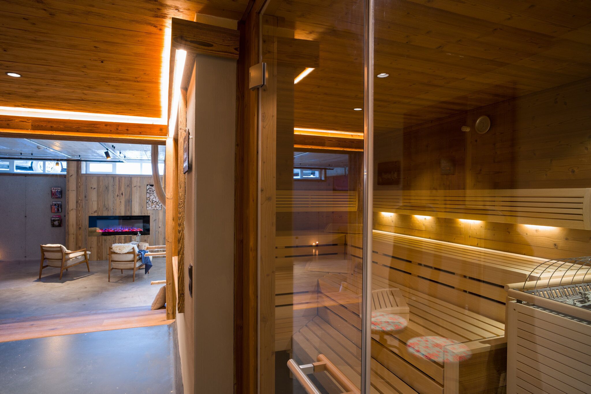 A modern interior with wooden paneling, a seating area with chairs, and a visible fireplace.