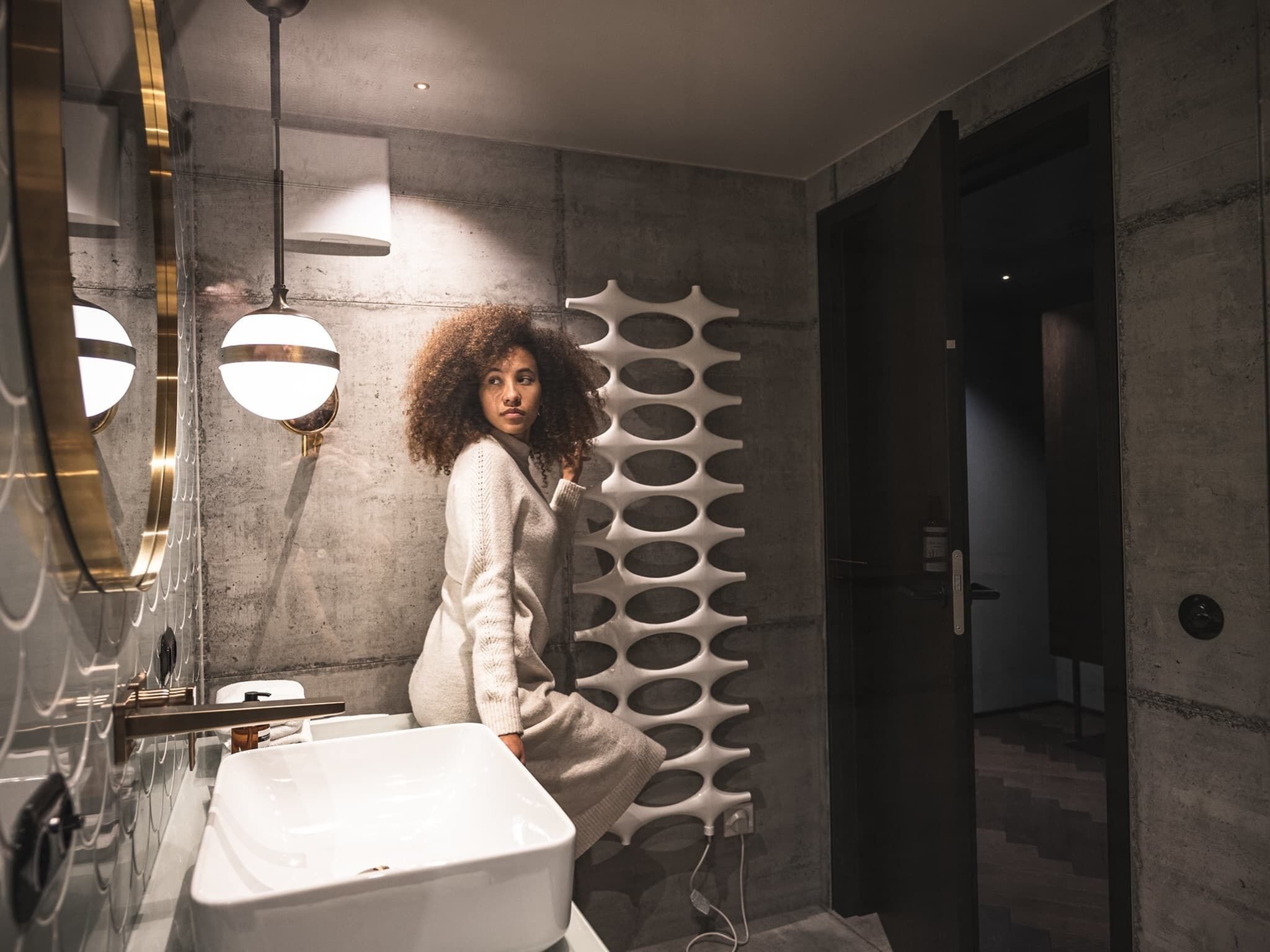 A modern bathroom with a large mirror, a white sink, and a unique wall design.
