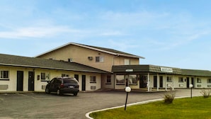 A motel with a parking lot, a covered parking area, and a sign indicating 'Welcome.' - America's Value Inn Mexico (Mexico)