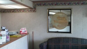 A reception desk with a mirror, a framed map, and a couch. - America's Value Inn Mexico (Mexico)