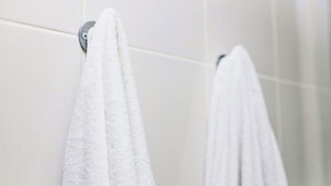 A bathroom with white tiled walls and two white towels hanging on a metallic towel rack. - America's Value Inn Mexico (Mexico)