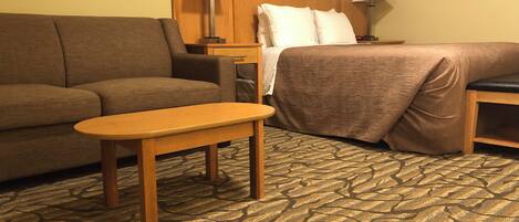 Quarto de hotel com cama, sofá, uma mesinha e duas luminárias de cabeceira.