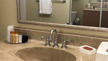 A bathroom with a large sink, two faucets, a mirror, and a towel rack.