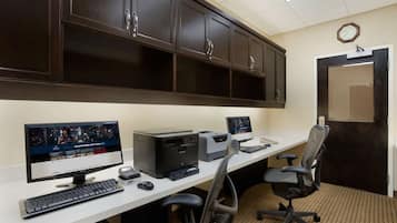 A modern office with a long desk, computer, printer, and office chairs.