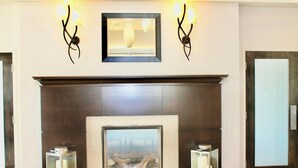 A modern lobby with a fireplace, framed artwork above, and wall-mounted lighting.