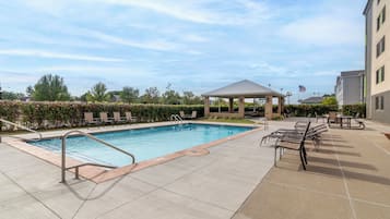 A swimming pool with lounge chairs and a gazebo.