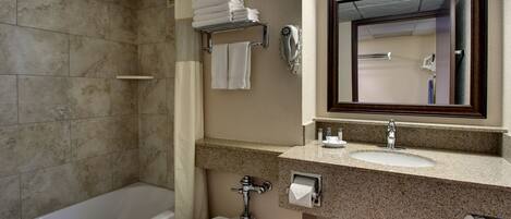 A bathroom with a bathtub, toilet, sink, and a mirror.