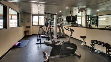 A gym with cardio equipment, weights, and a mirror.