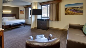A hotel room with a bed, a desk, a TV, a couch, and a painting on the wall.