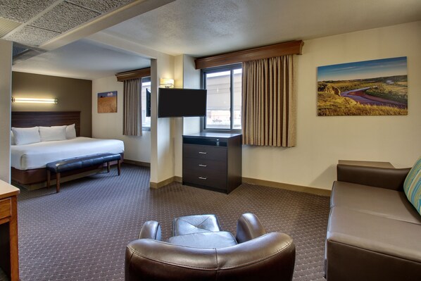 A hotel room with a bed, a desk, a TV, a couch, and a painting on the wall.