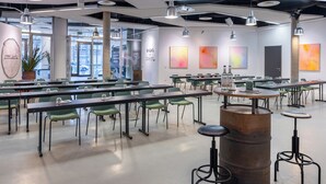 Una sala de conferencias moderna con mesas y sillas, un barril grande y arte abstracto en las paredes.