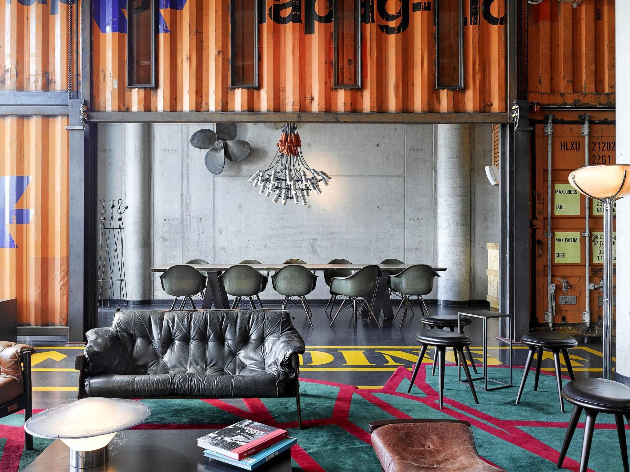 Un intérieur moderne avec un canapé en cuir, un coin repas et un tapis aux couleurs vives.