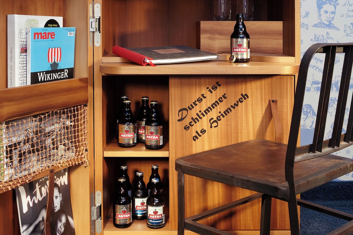 Un escritorio de madera con un globo terráqueo, una computadora portátil y tres botellas de cerveza.