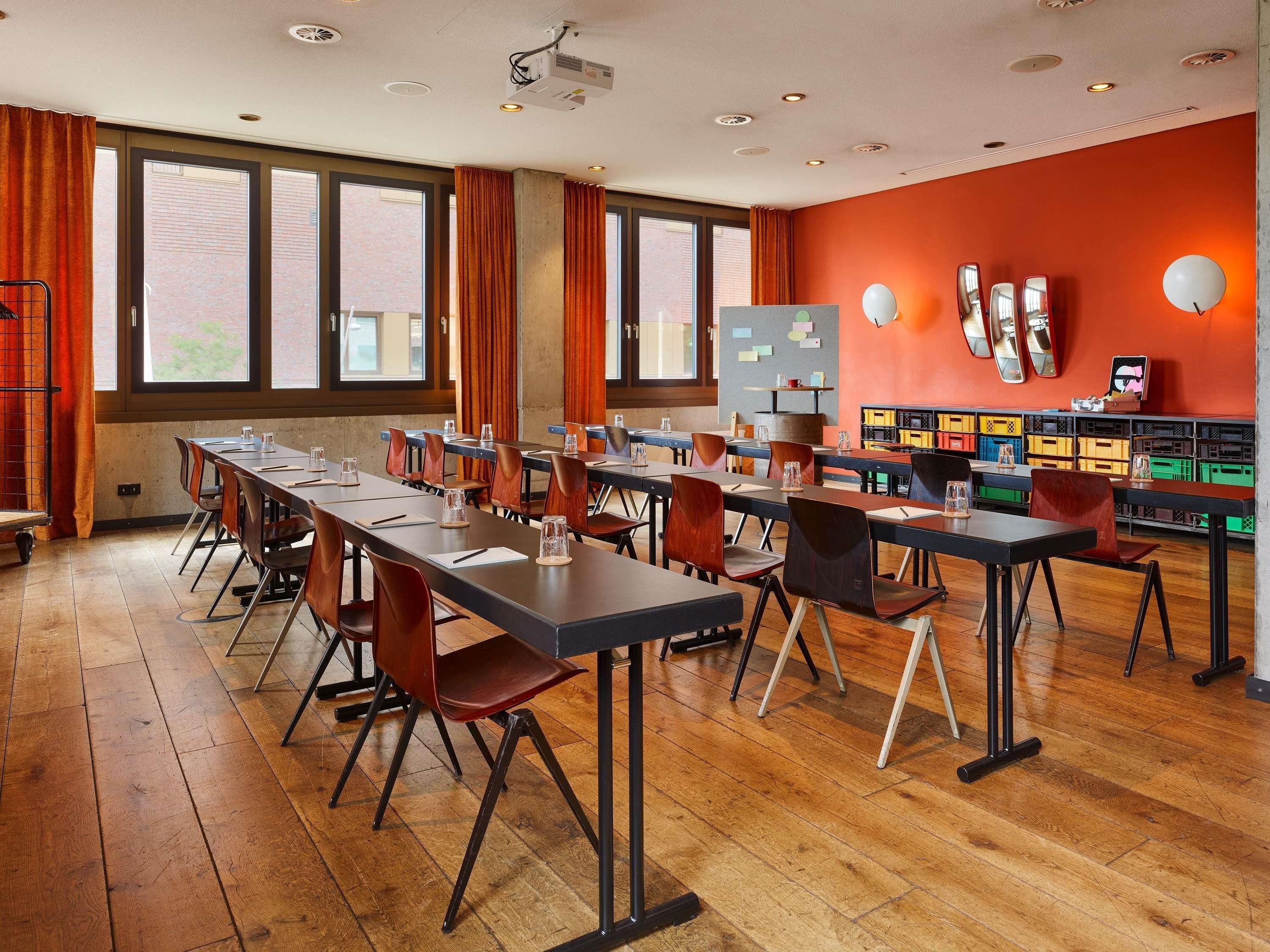 A conference room with long tables, chairs, and a projector.