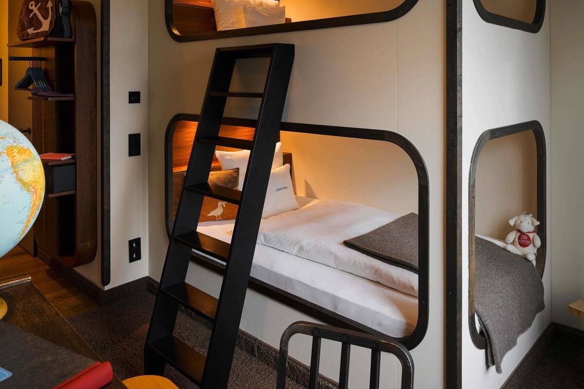 A bunk bed with a ladder, a globe, and a stuffed toy on a shelf.