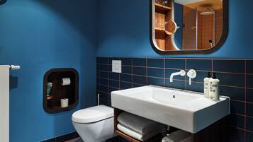 Un bagno moderno con un lavandino bianco, un water e uno specchio sopra il lavandino.