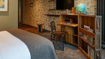 Un dormitorio con cama, escritorio, silla, estantería, un globo terráqueo y televisor.