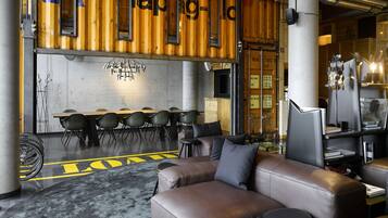 A modern interior with a long table and chairs, leather sofas, and a unique ceiling design.