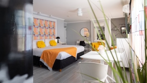 Ein modernes Hotelzimmer mit einem Bett, einem Schreibtisch und einem Sessel. An der Wand befindet sich ein Spiegel und ein Fenster mit Vorhängen.