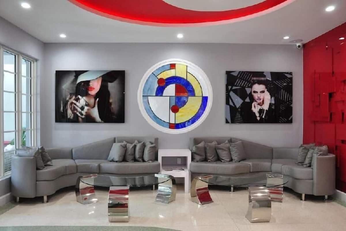 A modern living room with a grey sectional sofa, a central coffee table, and three abstract paintings on the wall.