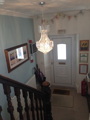 A staircase with a chandelier, a framed picture, and a door with a window.
