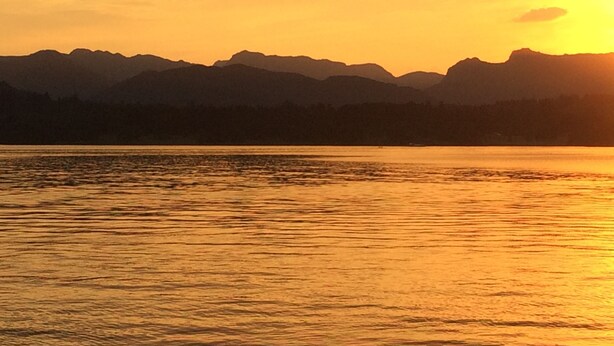A sunset over a mountain range with a calm lake in the foreground. - Invergarry Room Only Guest House (Windermere)