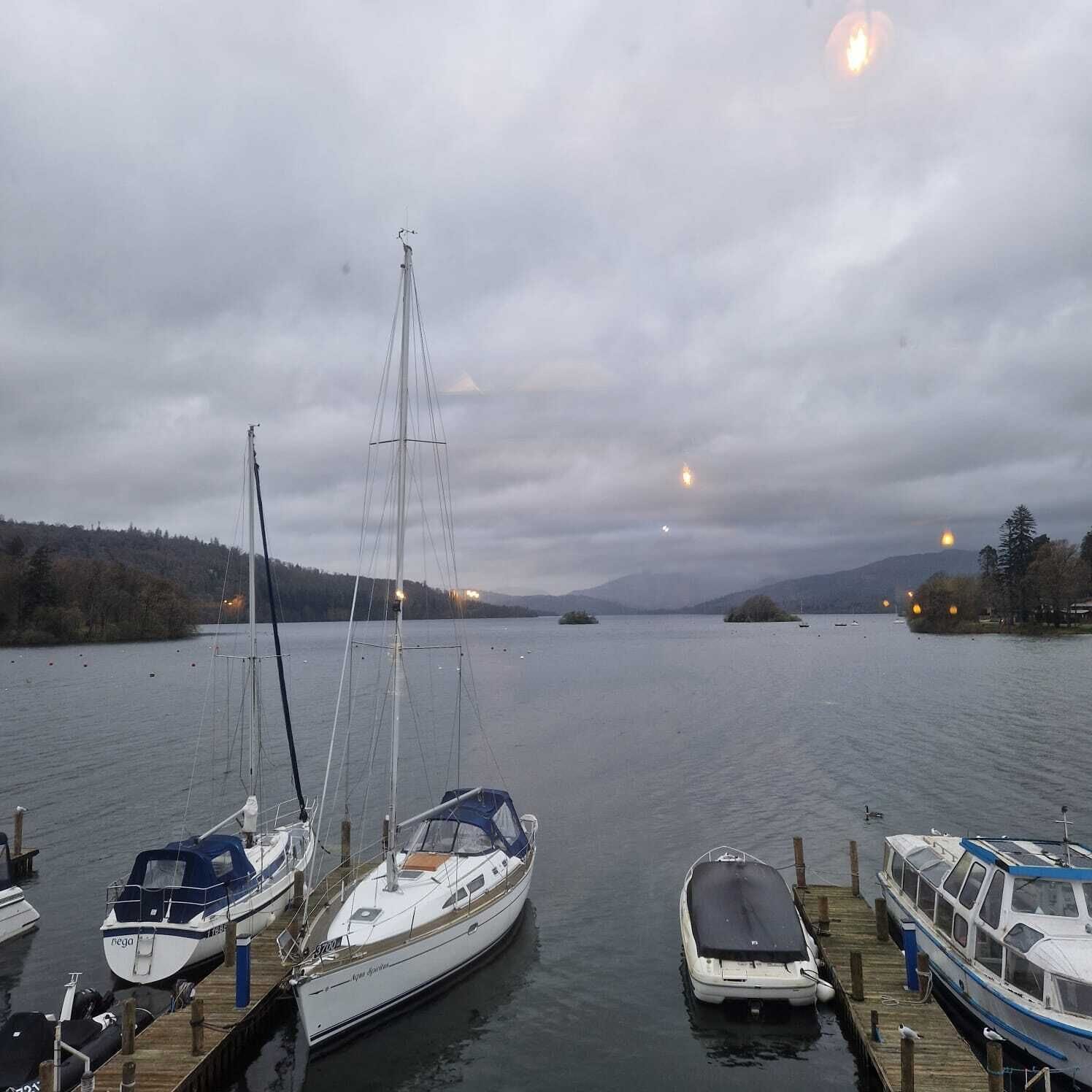 A marina with several boats docked, including a sailboat and a motorboat.