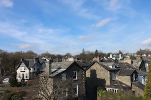 A cluster of stone houses with steep roofs, surrounded by trees and a clear sky.