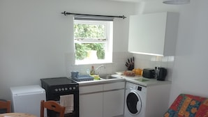Une cuisine compacte équipée d’un lave-linge, d’une table à manger avec des chaises et d’un canapé.
