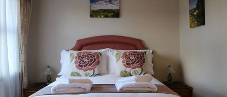 A neatly made bed with two pillows, a headboard, and two bedside tables with lamps.