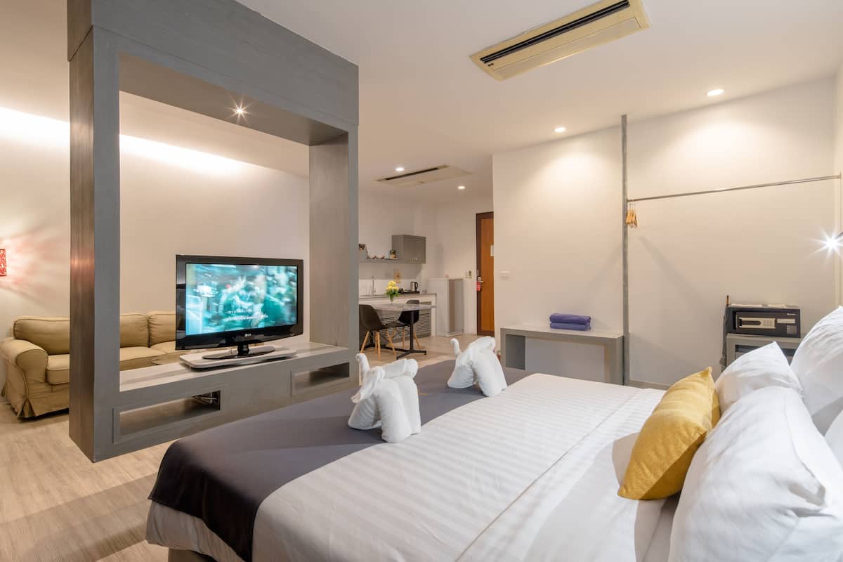 Una habitación de hotel moderna con una cama, televisión, escritorio y zona de estar.