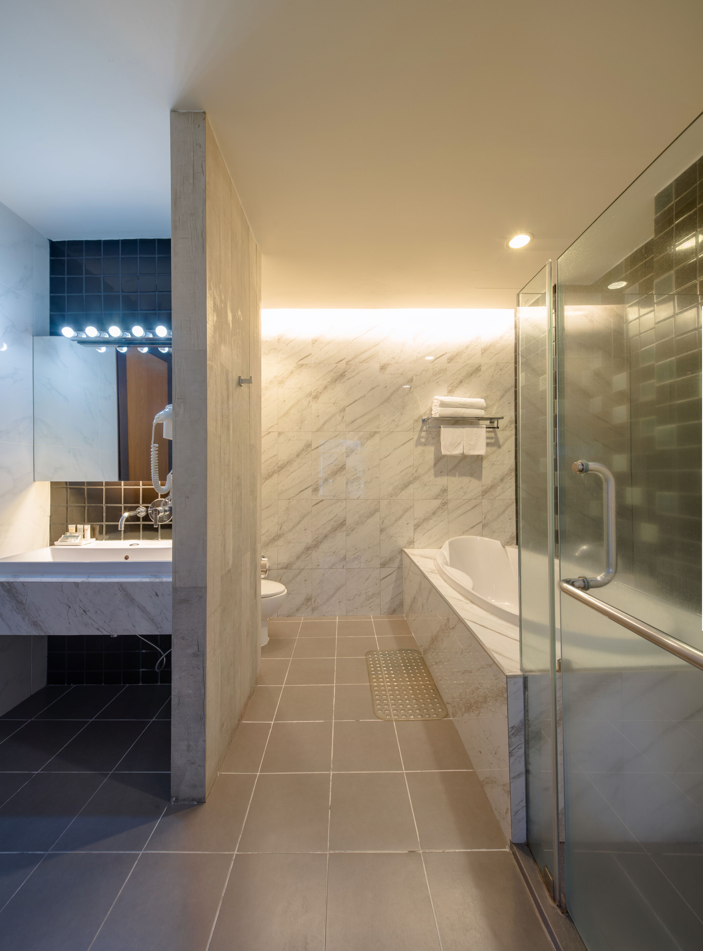 A modern bathroom with a glass-enclosed shower, a standalone bathtub, and a vanity with a mirror.