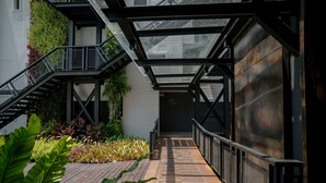 Une allée extérieure couverte, dotée d’une terrasse en bois, de rampes en métal et d’une structure de toit en verre.