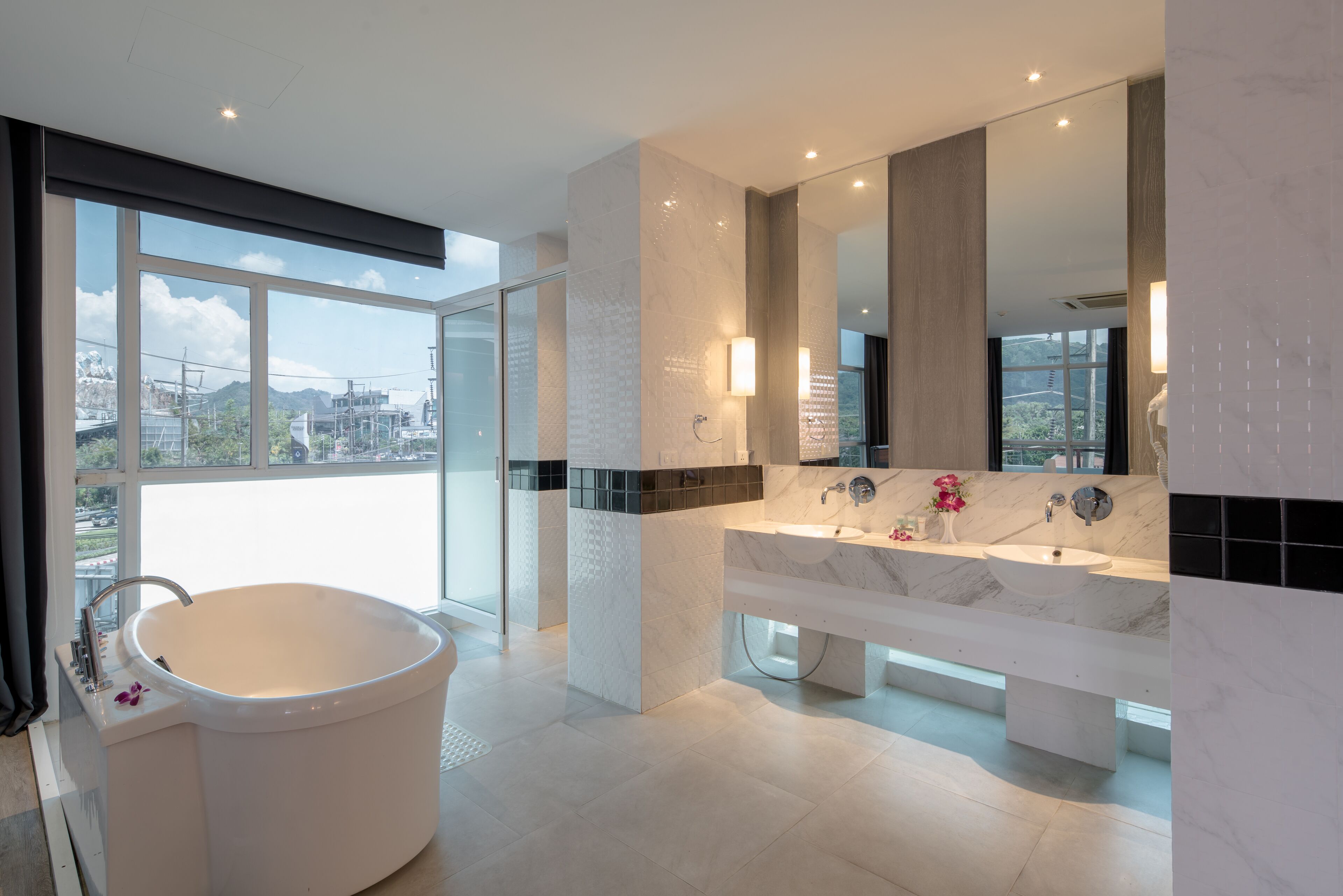 A modern bathroom with a large bathtub, a double sink vanity, and a large mirror.