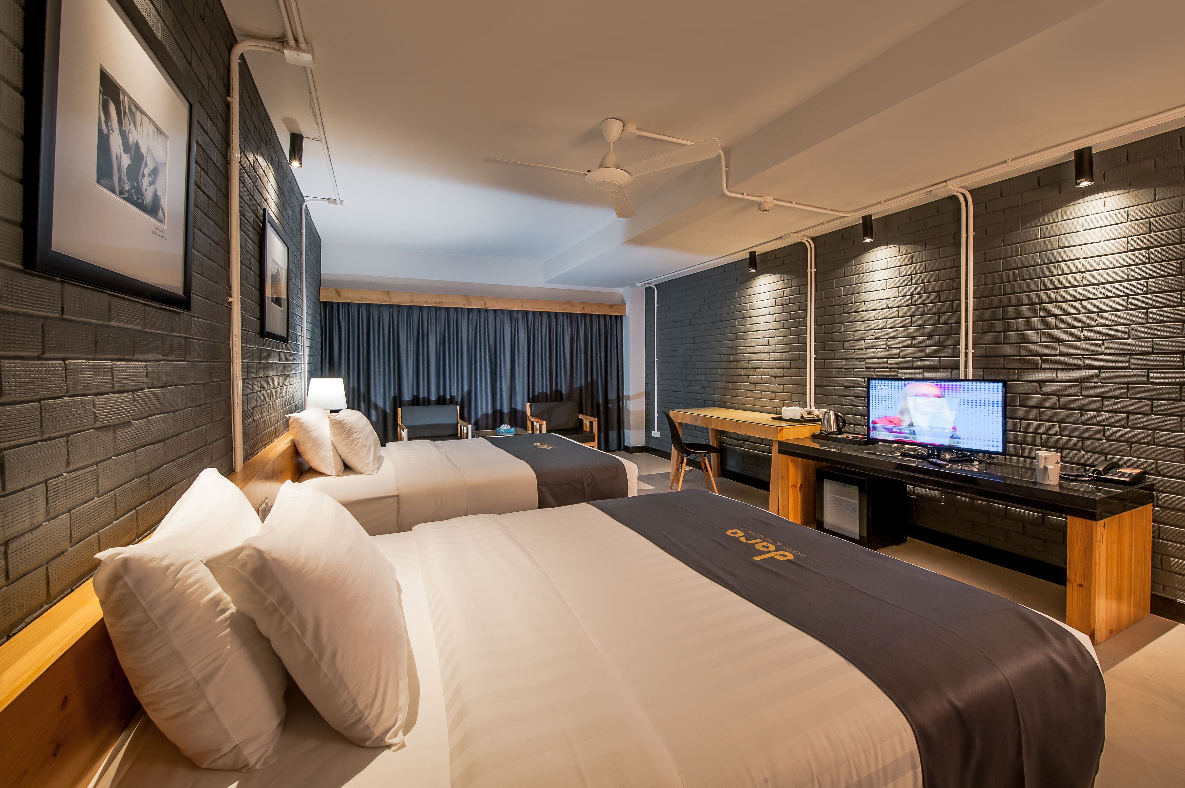 A modern hotel room with two beds, a desk with a computer, and a television.