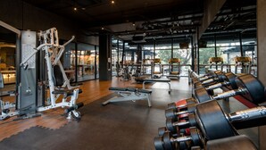 Une salle de sport équipée de divers appareils d’exercice, dotée de grandes fenêtres et présentant un aménagement intérieur moderne.