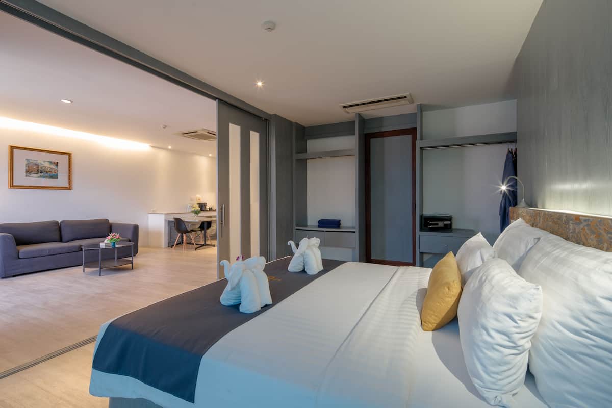 Una habitación de hotel moderna con una cama grande, un sofá, un escritorio y un comedor.