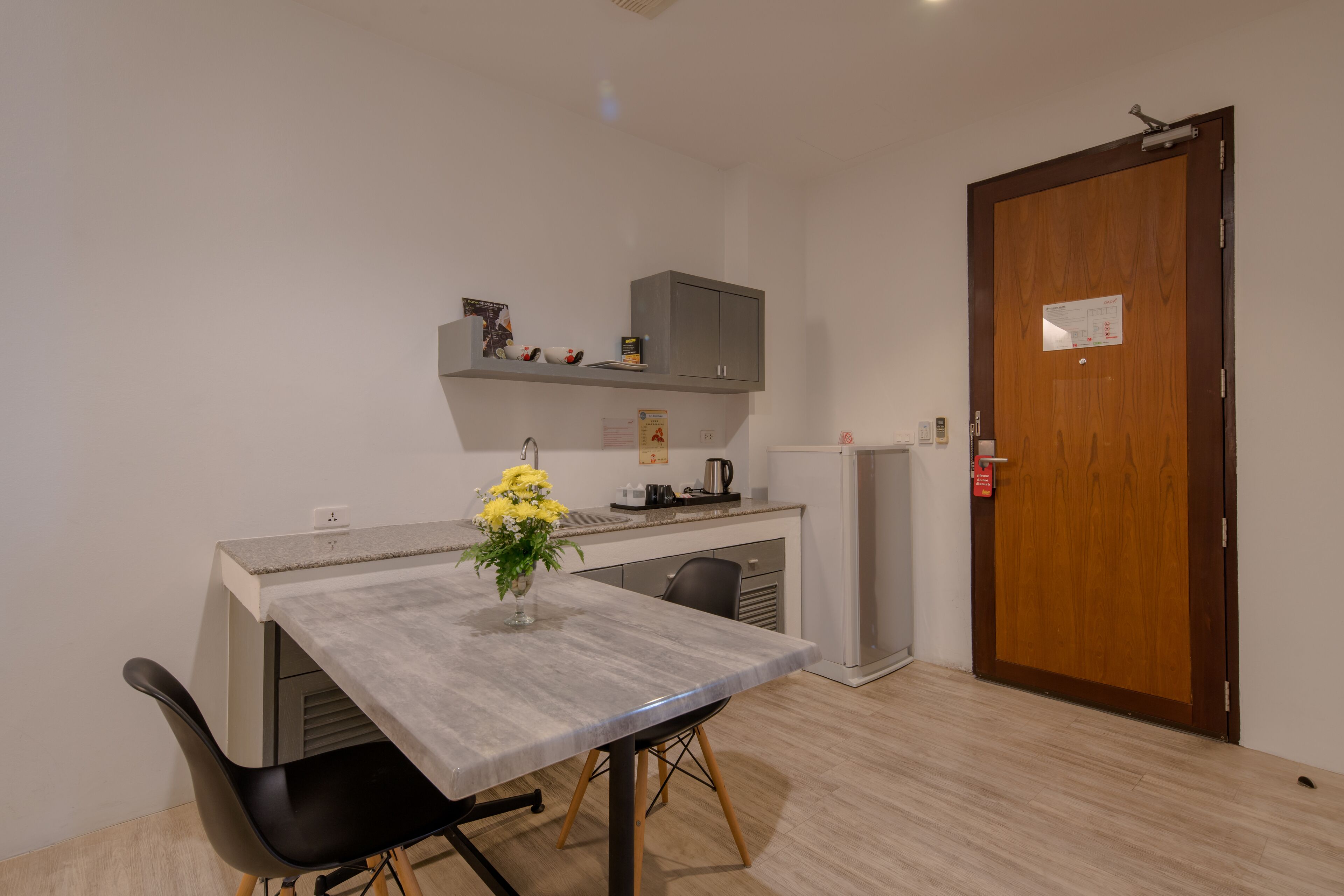Una cocina compacta con una mesa de comedor, un jarrón de flores y una puerta de madera.