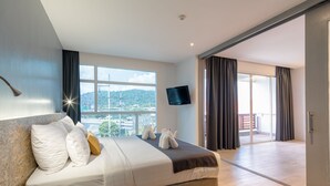 Une chambre d’hôtel moderne dotée d’un grand lit, d’une télévision à écran plat et d’un balcon offrant une vue sur la ville.