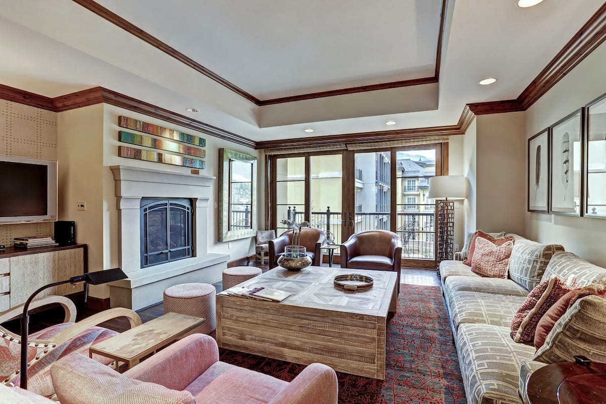 A spacious living room with a fireplace, comfortable seating, and large windows offering a view of the outside.