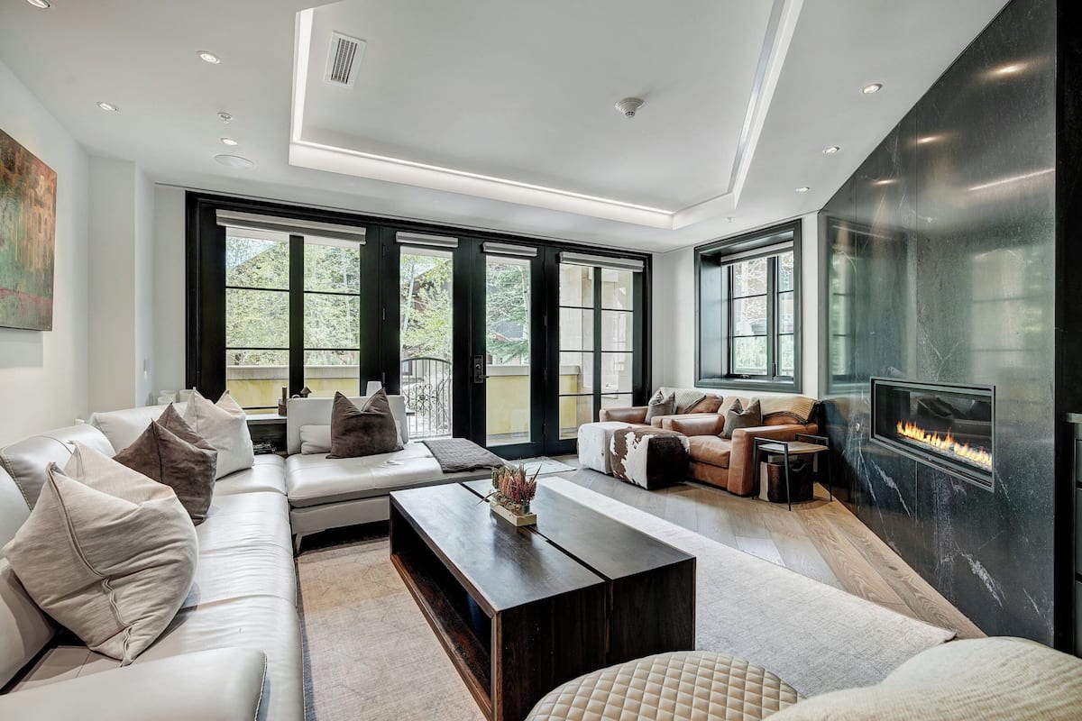 A modern living room with a sectional sofa, a coffee table, and a fireplace.