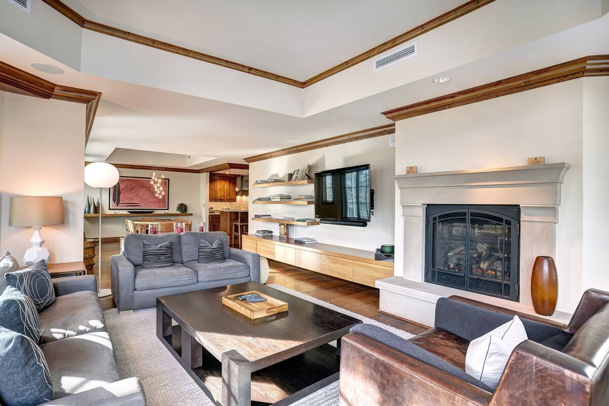 A spacious living room with a fireplace, a television mounted above it, and a cozy seating area with sofas and a coffee table.