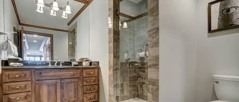 A modern bathroom with a wooden vanity, a glass shower enclosure, and a white toilet.