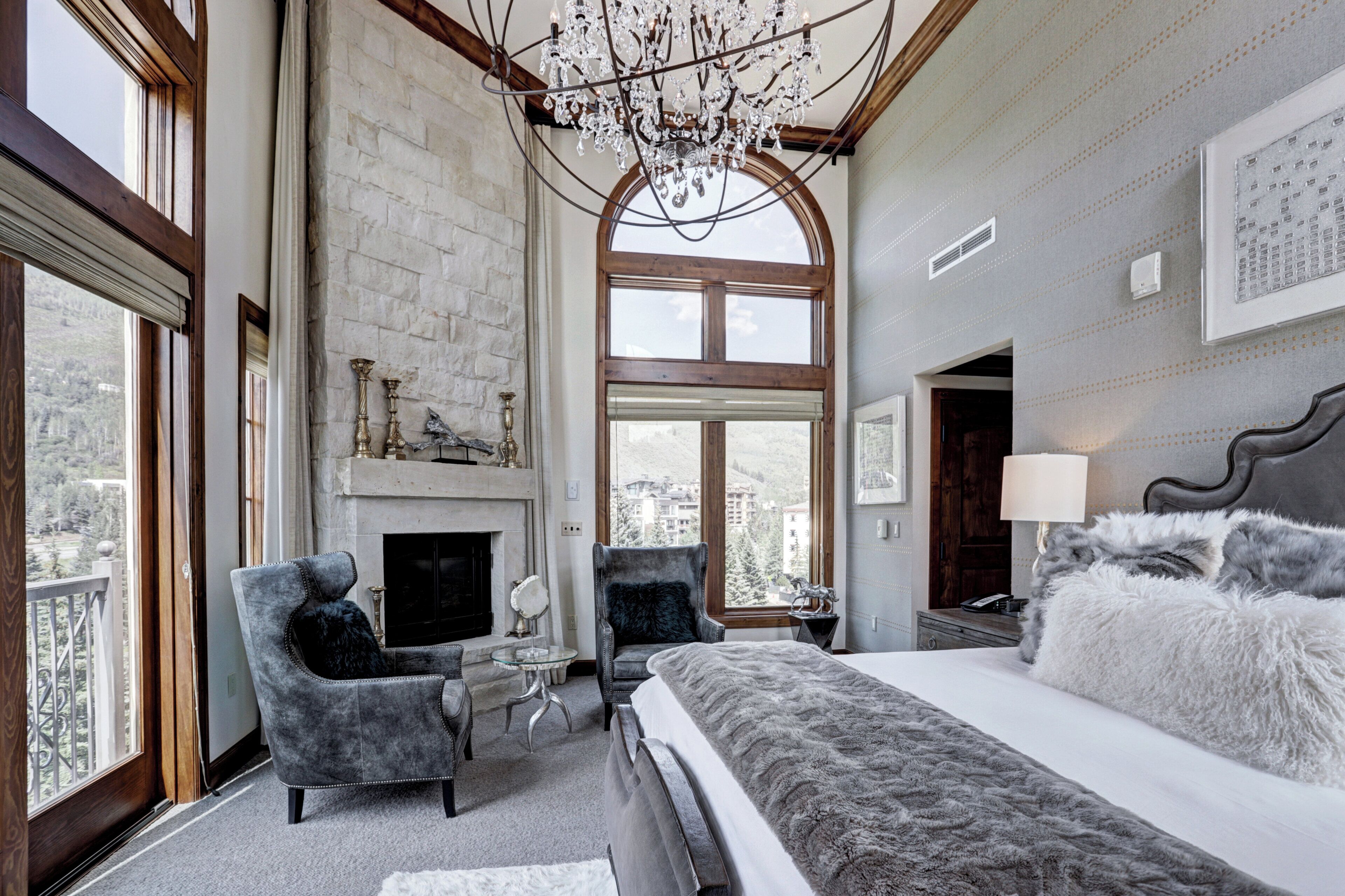 Un dormitorio espacioso con una cama grande, dos sillones, una chimenea y un candelabro.