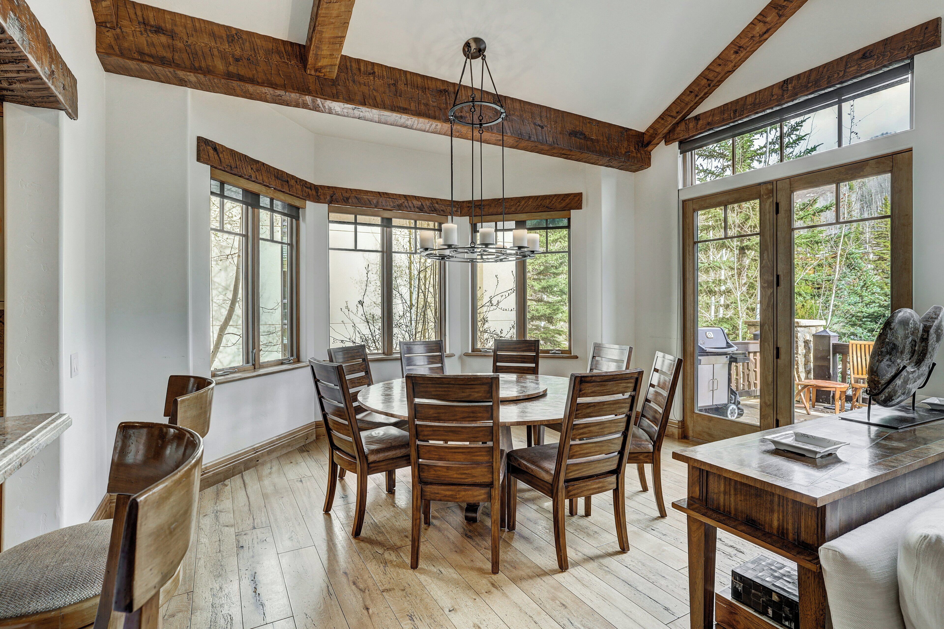 A dining area with a round table, wooden chairs, and a chandelier.