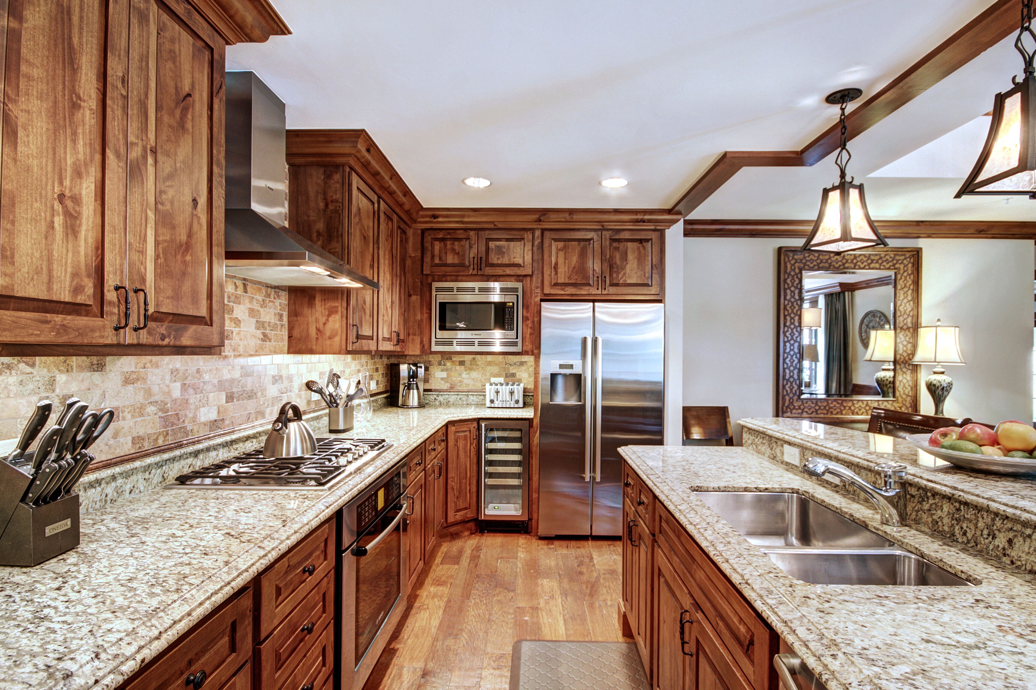 Una cocina con armarios de madera, electrodomésticos de acero inoxidable, encimeras de granito y una isla grande con fregadero.