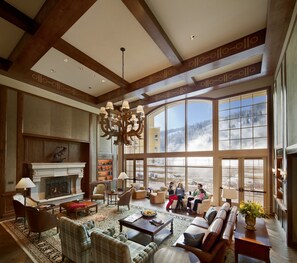 A spacious living room with a fireplace, comfortable seating, and a large window offering a view of a snowy landscape.