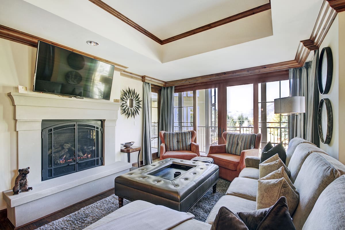A living room with a fireplace, a television, and a large window with curtains.