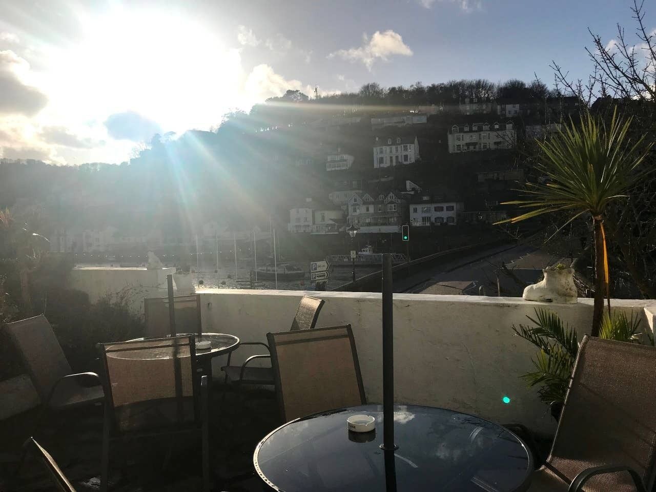 Una terrazza con tavolo e sedie, affacciata su una città con edifici e una collina sullo sfondo.
