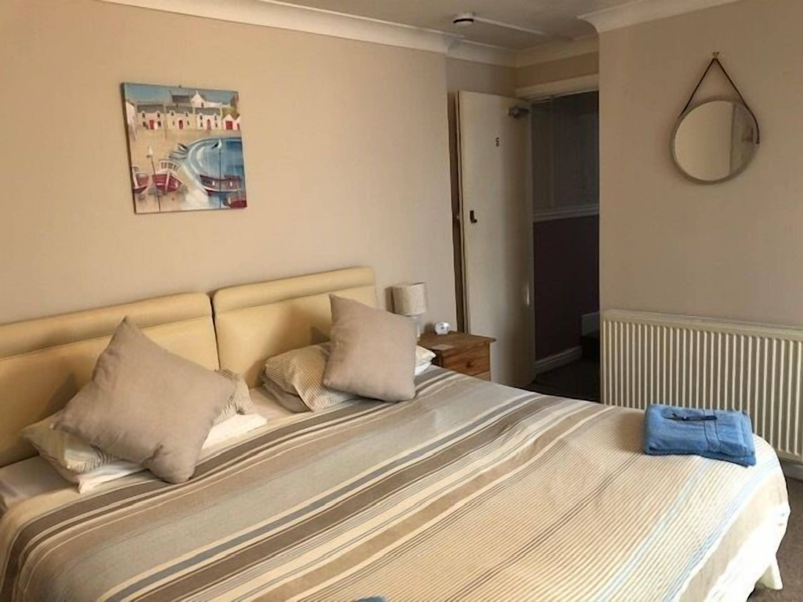 Una habitación de hotel con una cama, una mesita de noche, una lámpara, un cuadro en la pared y un radiador.